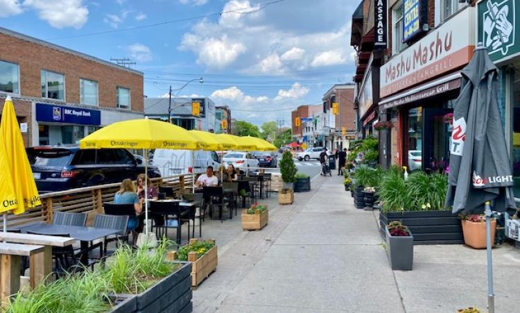 Photo of CafeTO on Spadina Rd yellow umbrellas and cafe tables in on street patios